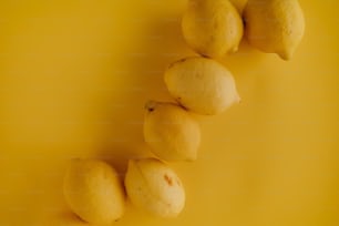 a group of lemons sitting on top of a yellow surface