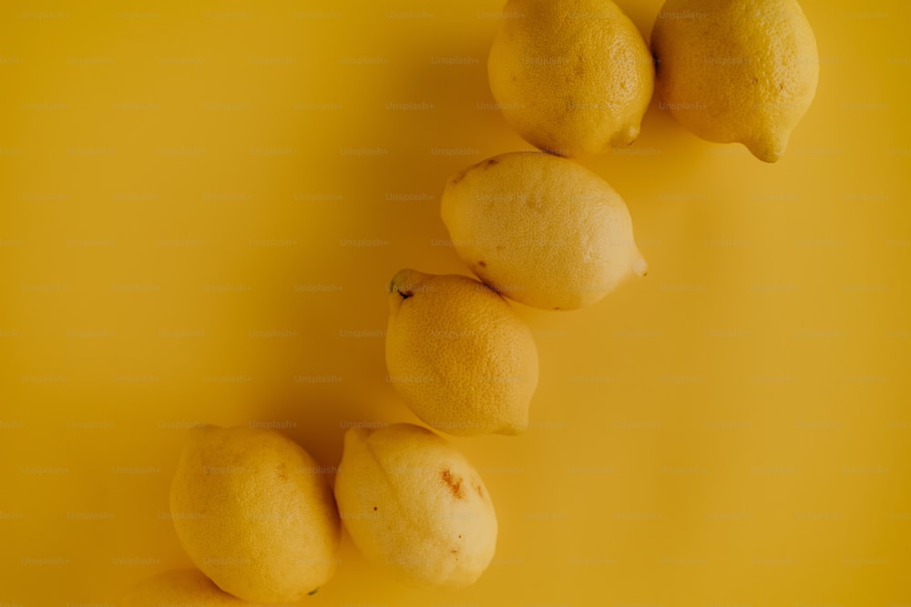 un gruppo di limoni seduti sopra una superficie gialla