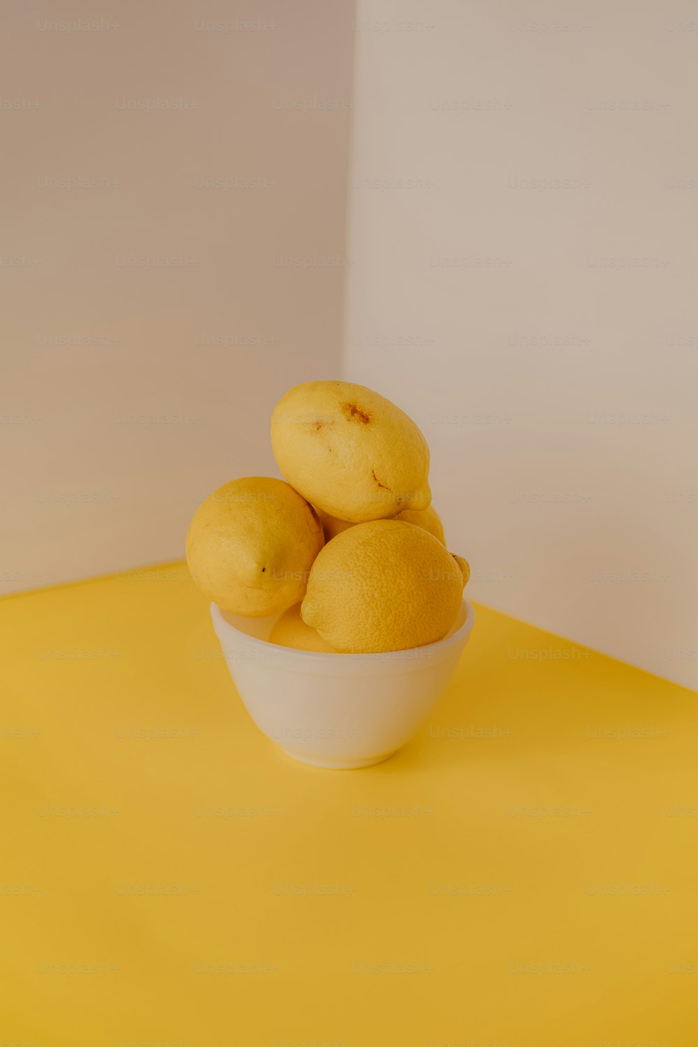 a bowl of lemons on a yellow table