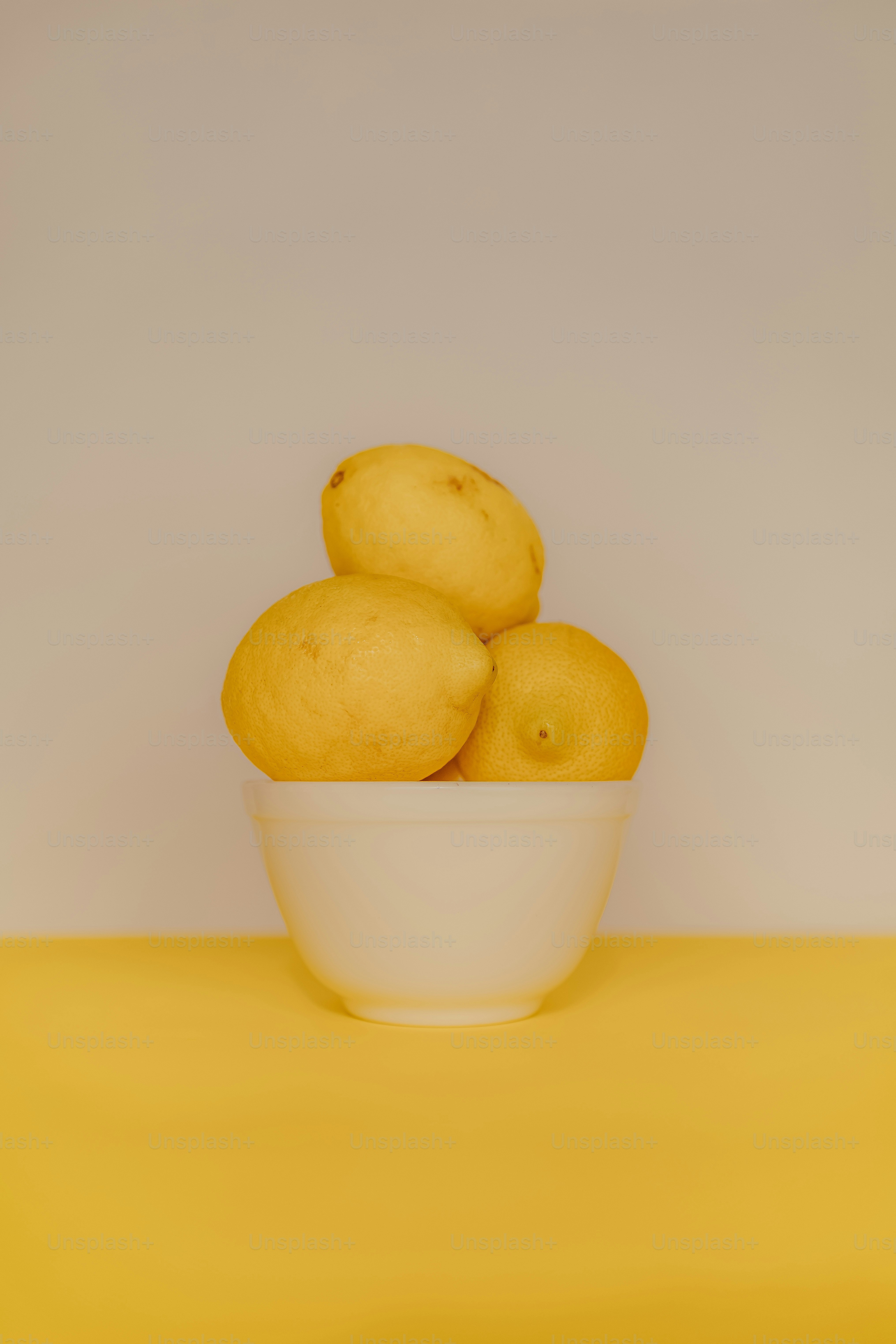 a bowl of lemons on a yellow table