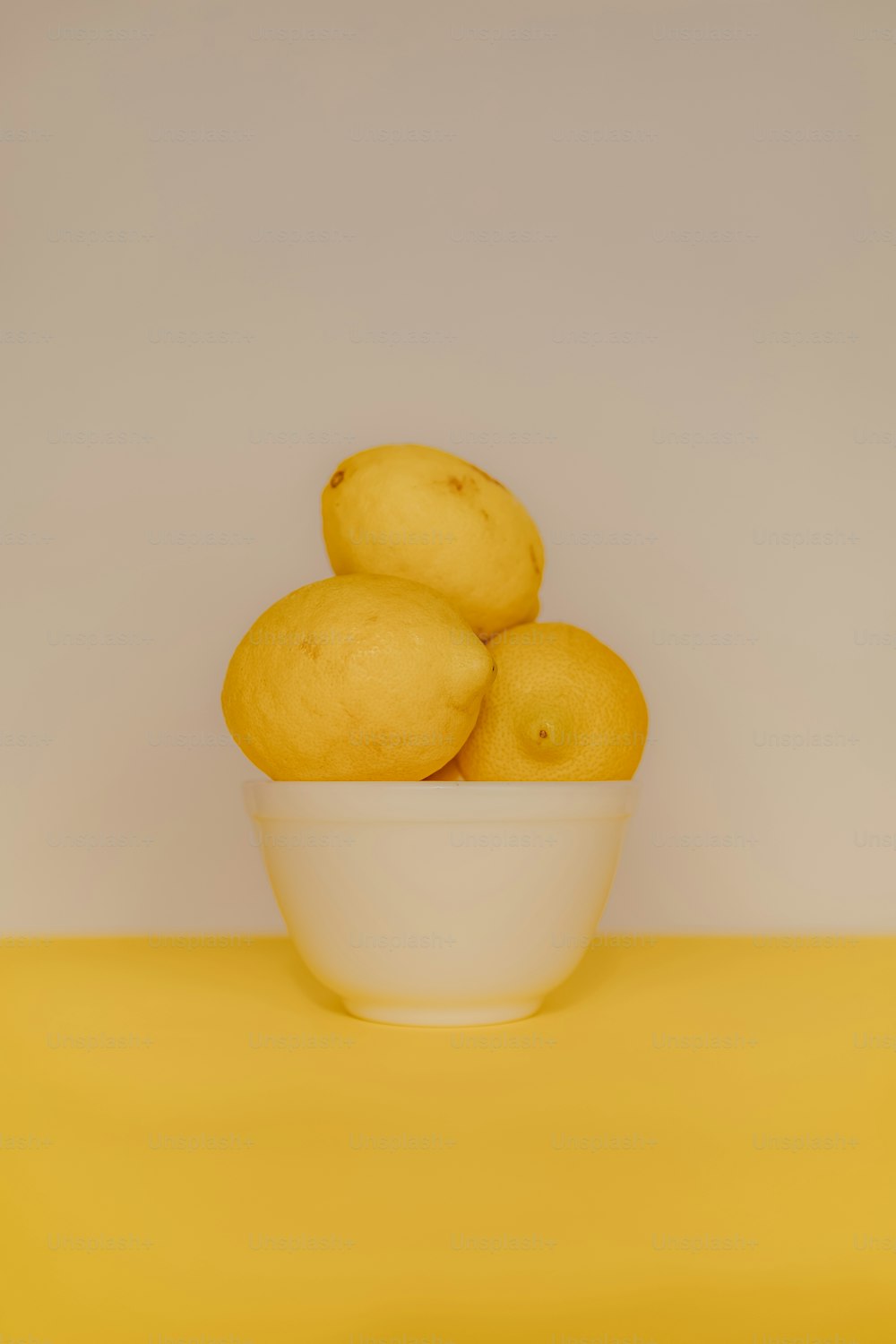 un bol de citrons sur une table jaune