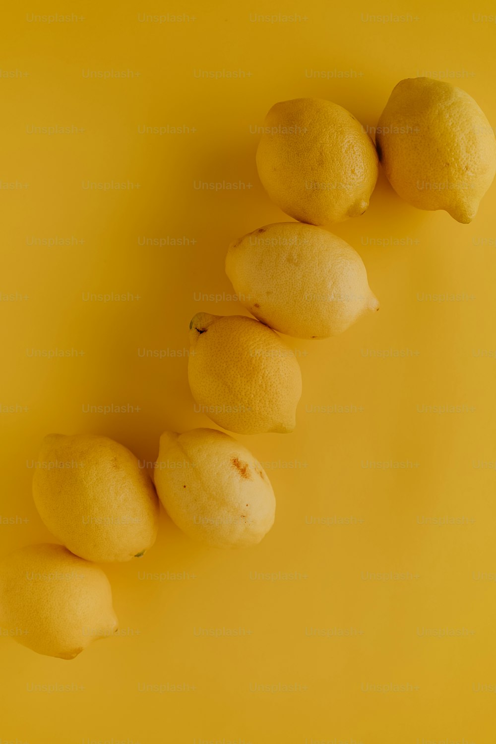 a row of lemons sitting on top of a yellow surface