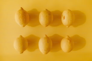 a group of lemons sitting on top of a yellow surface