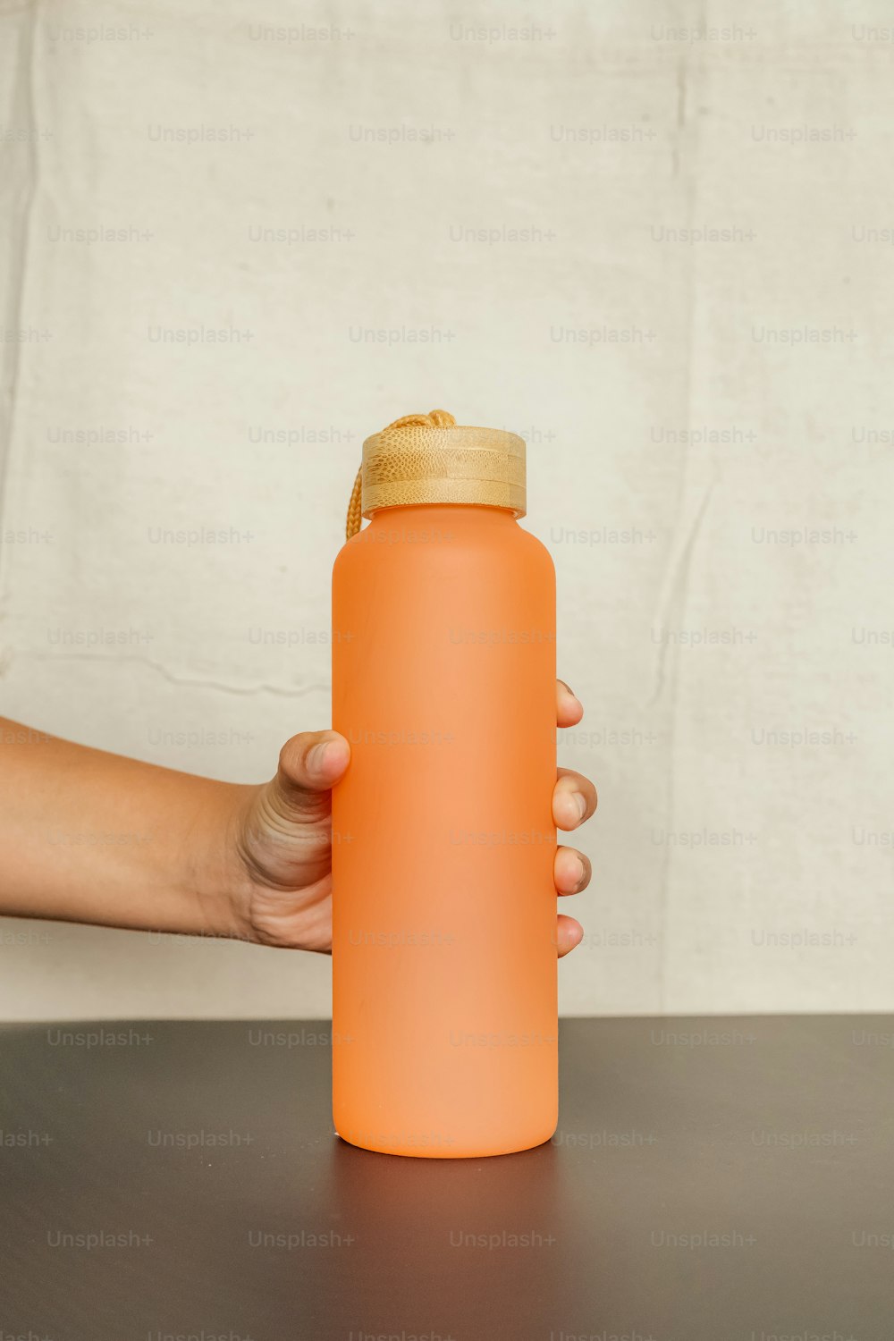 una persona sosteniendo una botella de agua sobre una mesa
