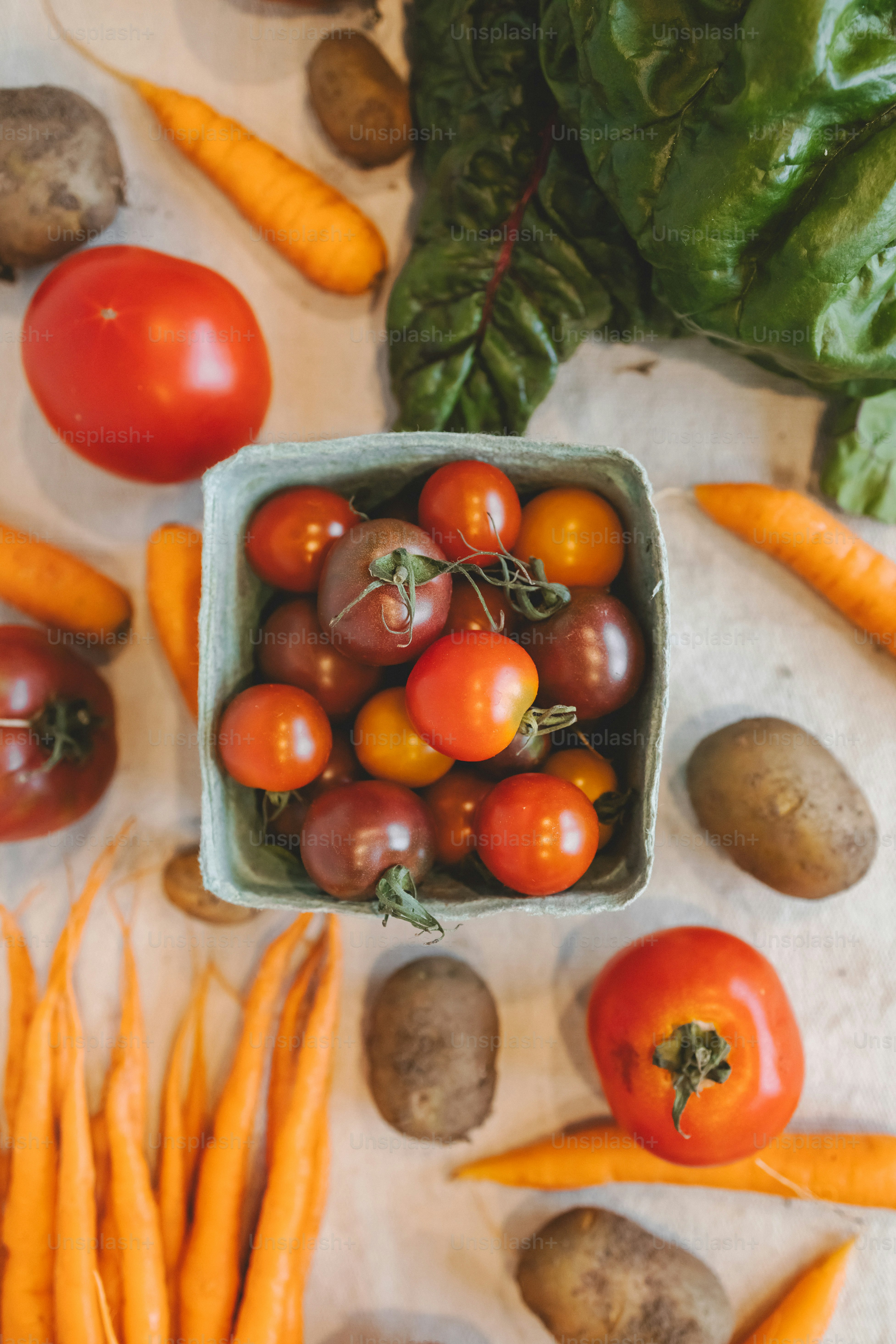 a bowl of tomatoes, carrots, and potatoes on a table