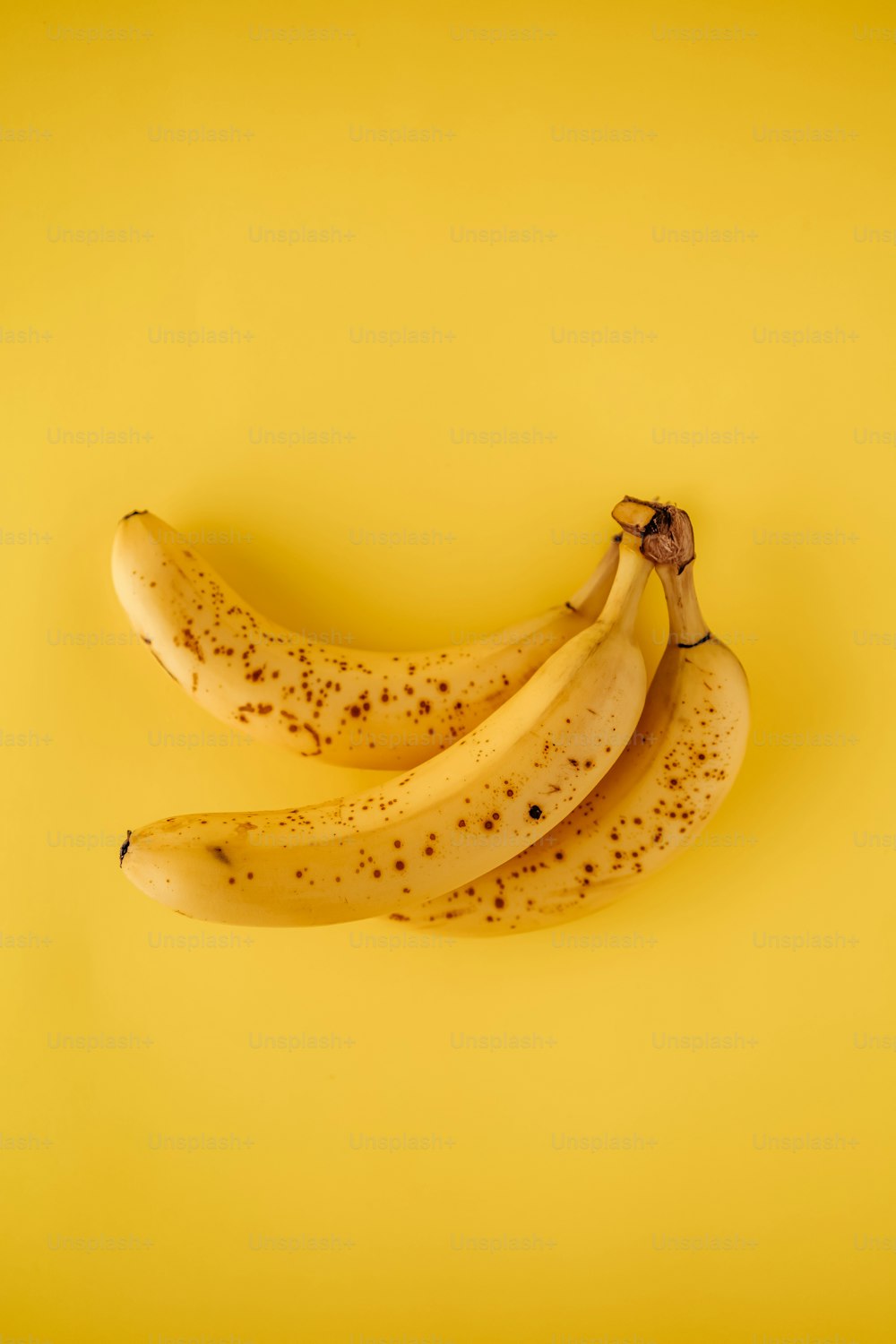 three ripe bananas on a yellow background
