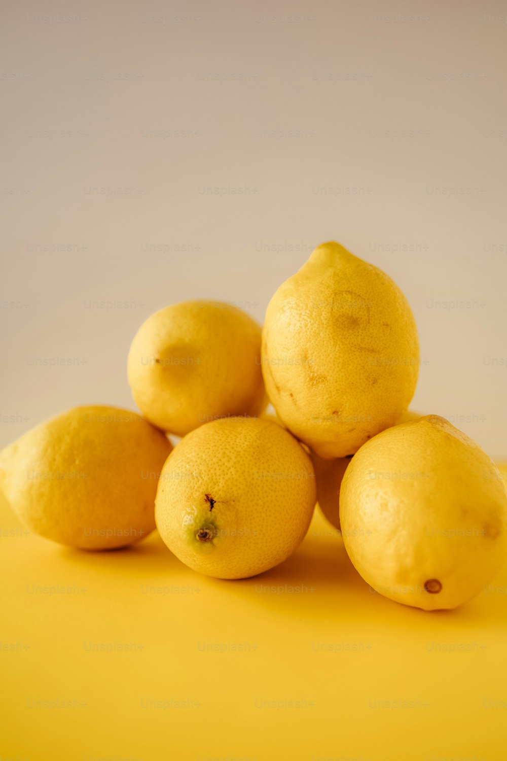 a pile of lemons sitting on top of a yellow surface