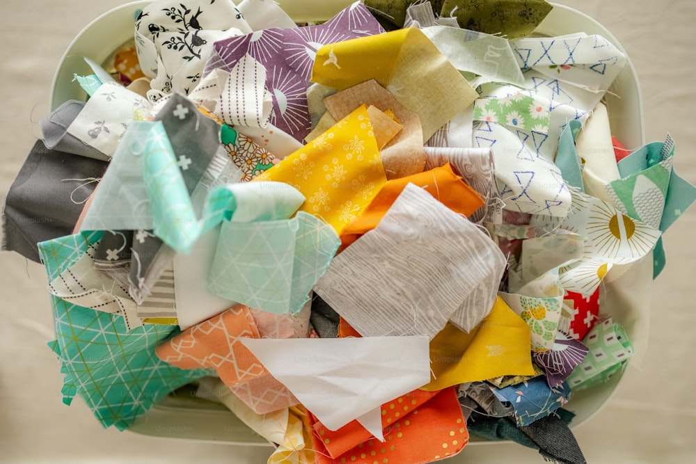 Un tazón blanco lleno de muchas telas de diferentes colores