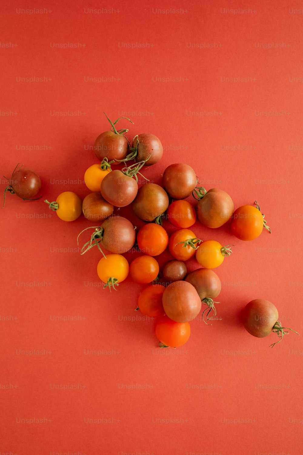 Un montón de tomates y naranjas sobre una superficie roja