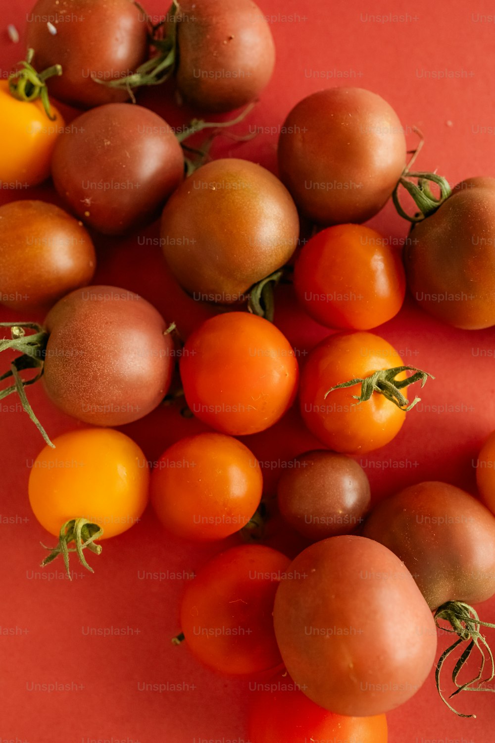 a bunch of tomatoes on a red surface