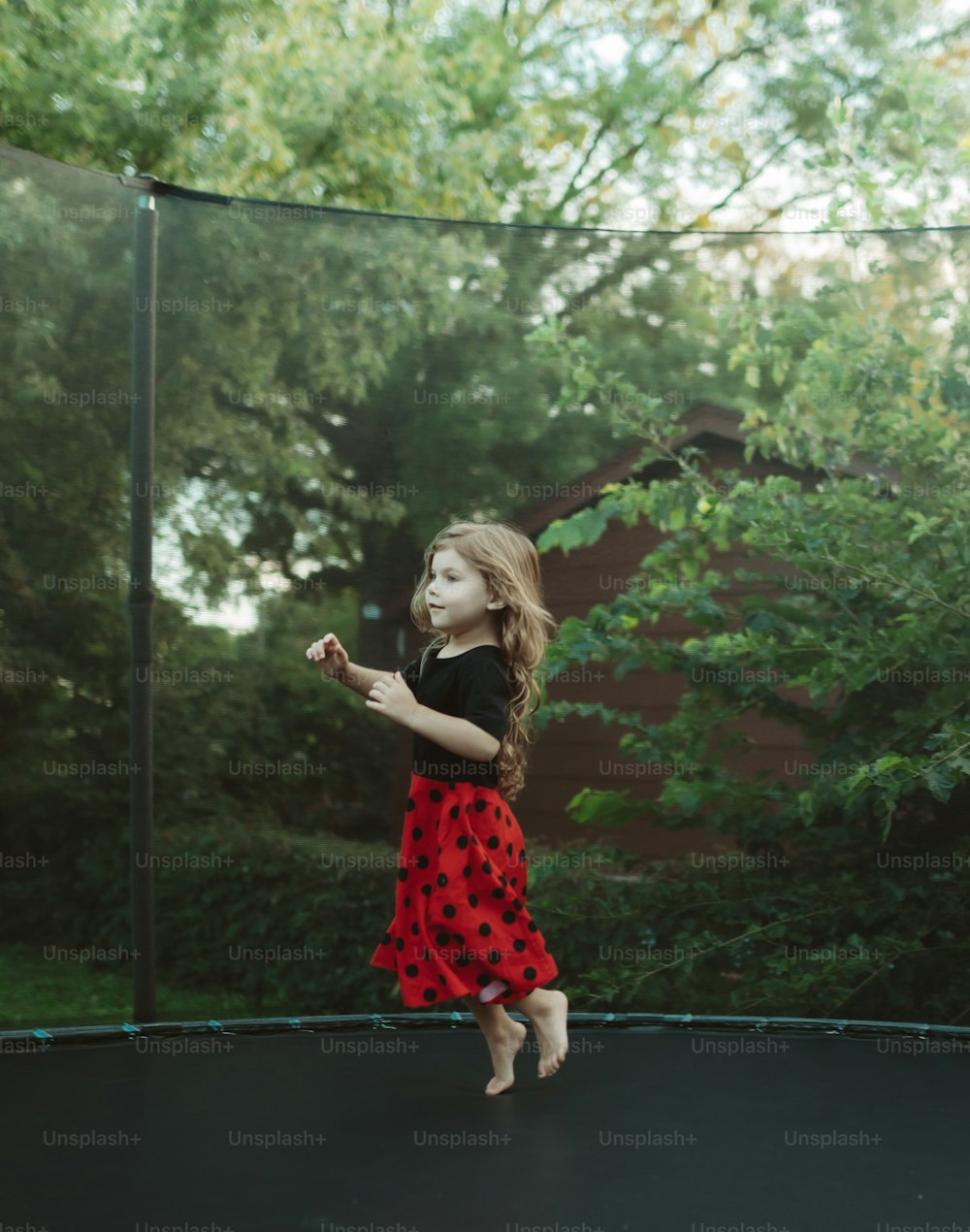 a little girl is jumping on a trampoline