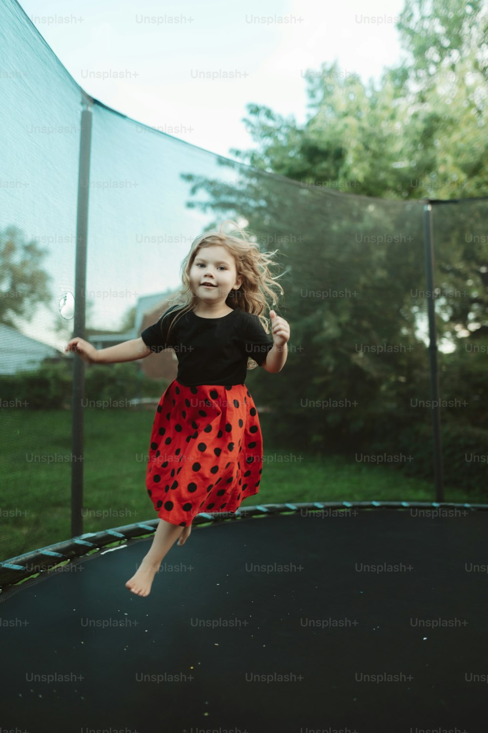 a little girl jumping on a trampoline outside