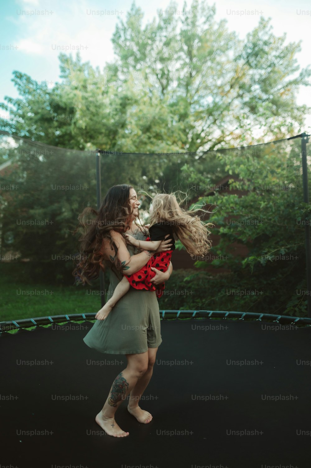 a woman holding a child on top of a trampoline