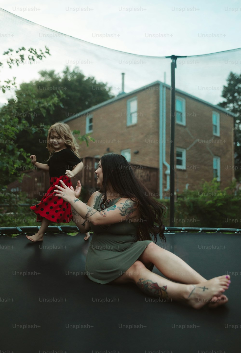 a woman sitting on top of a trampoline holding a little girl