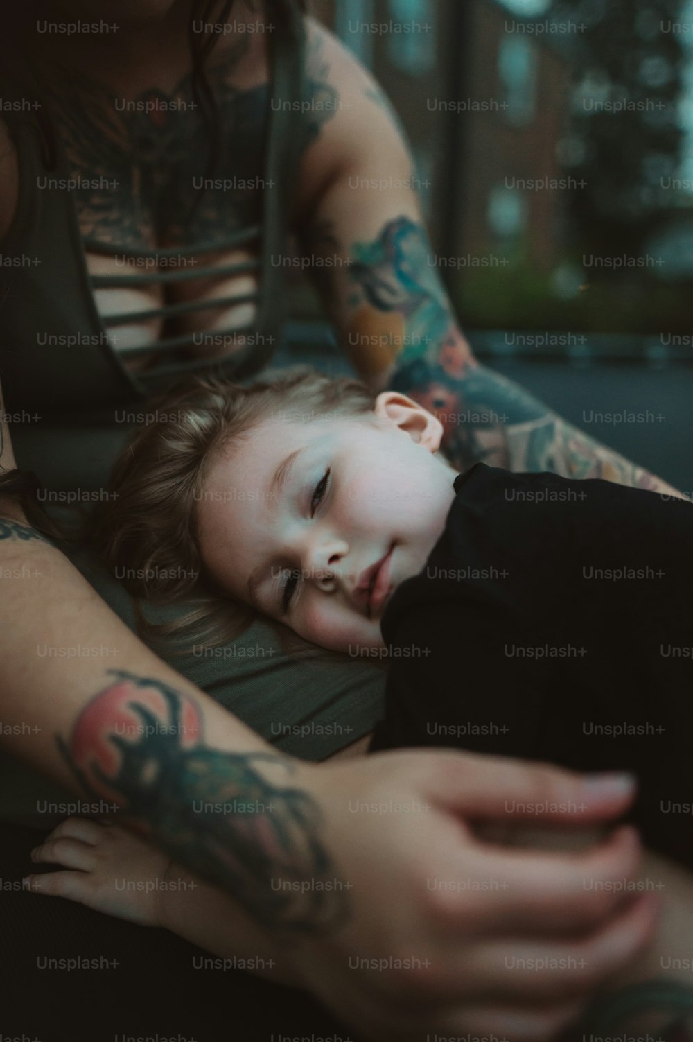 a woman with tattoos on her arm holding a child