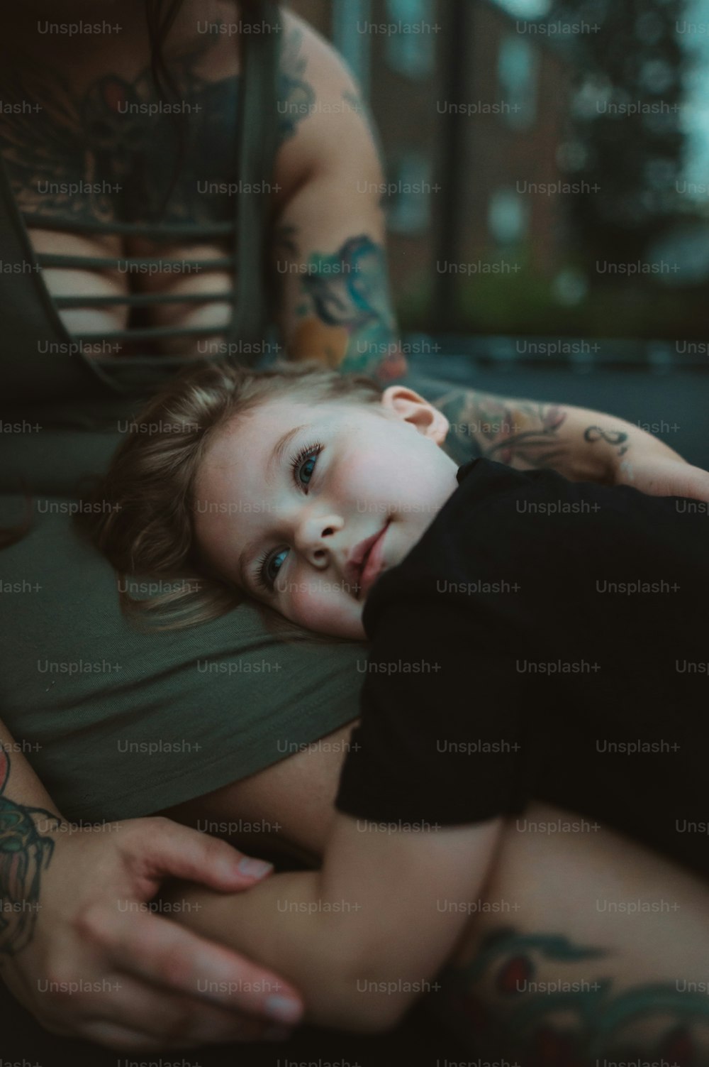 a little boy is laying on a woman's lap