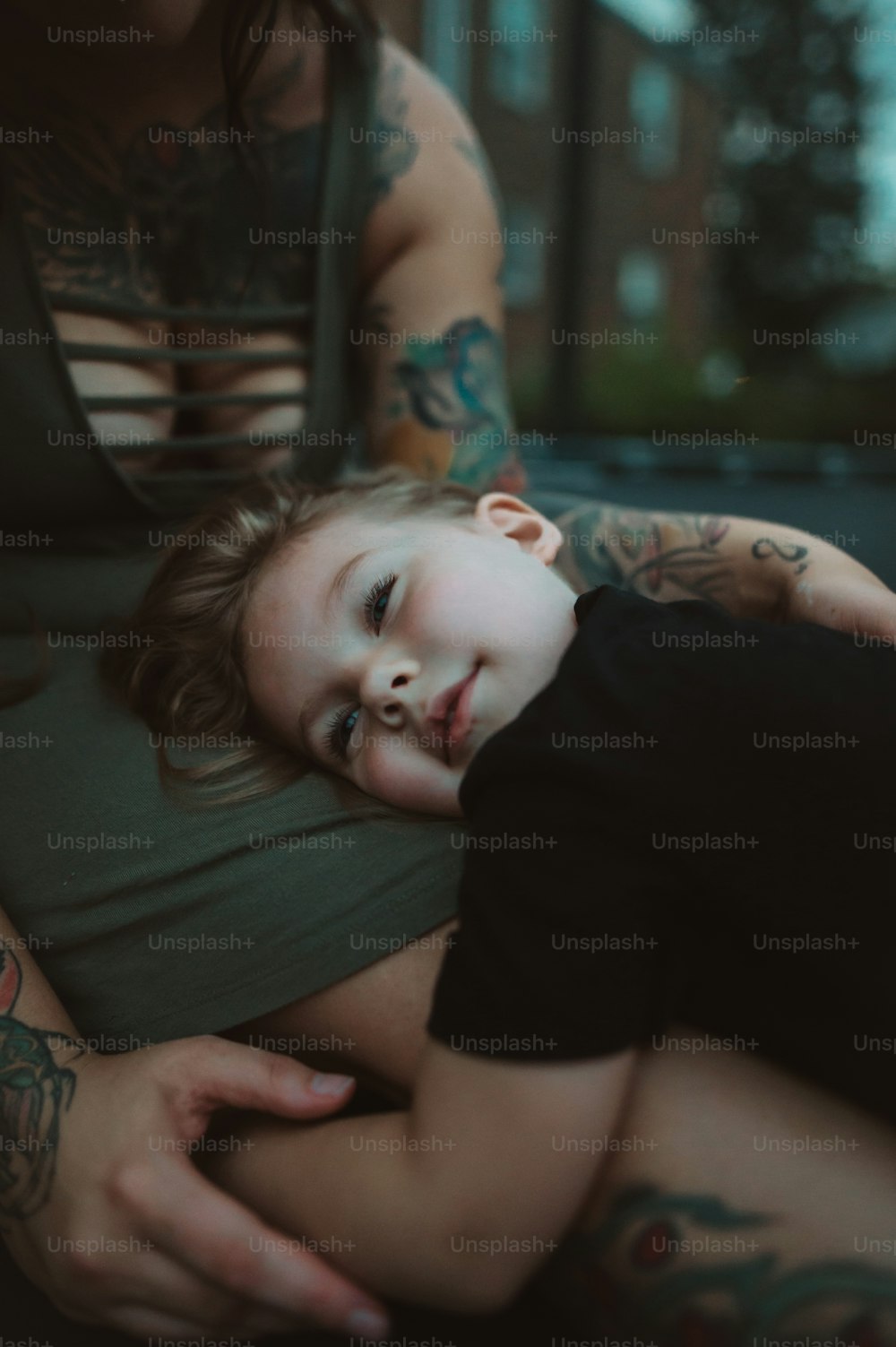 a woman holding a child with tattoos on her arms