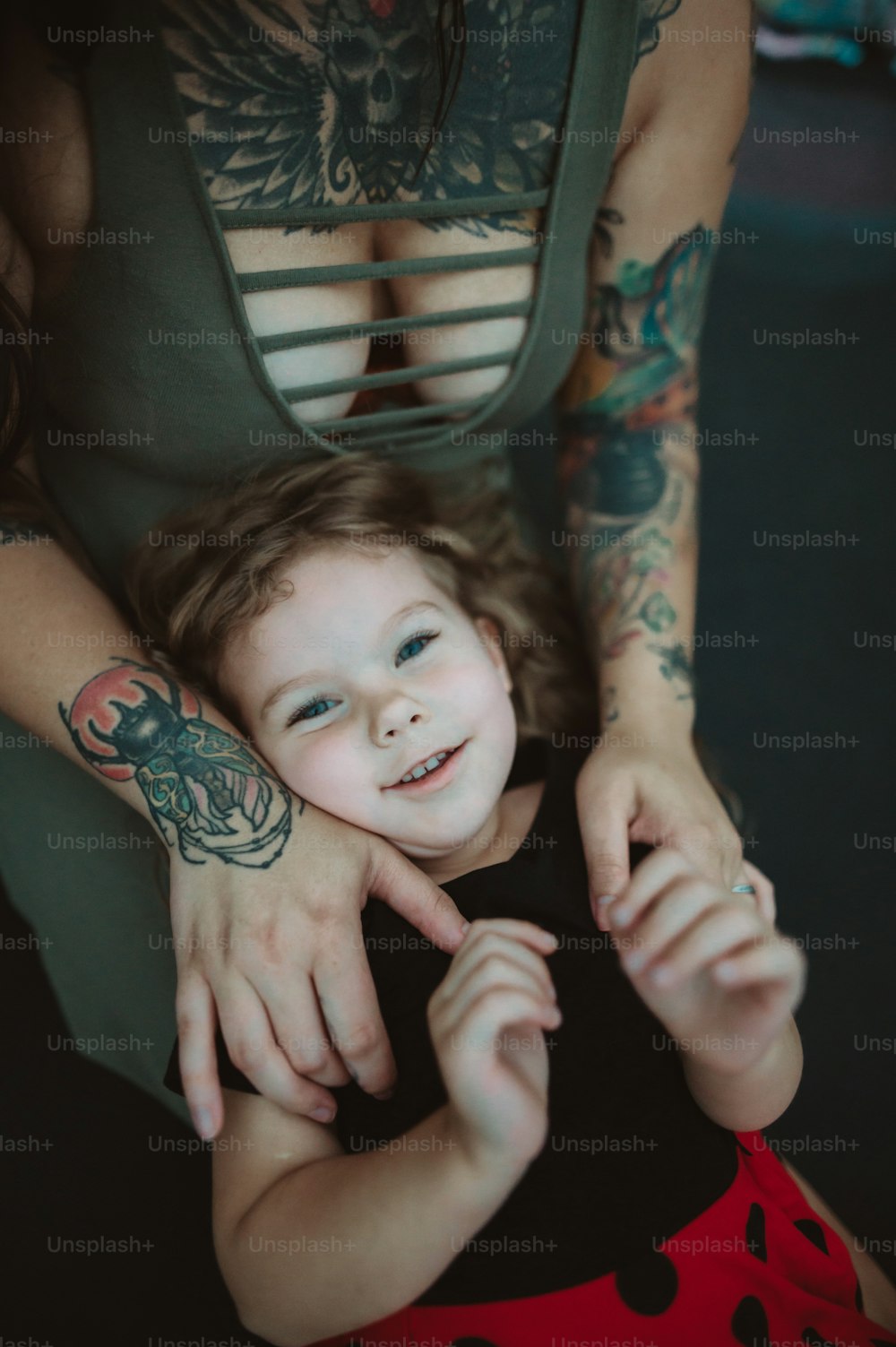 a woman holding a little girl with tattoos on her arms
