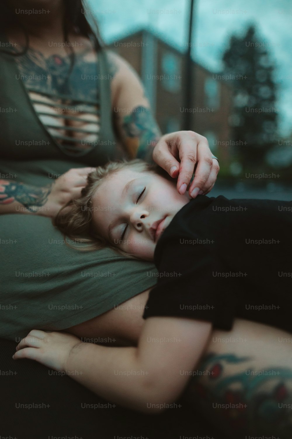 Una mujer sosteniendo a un niño con tatuajes en sus brazos