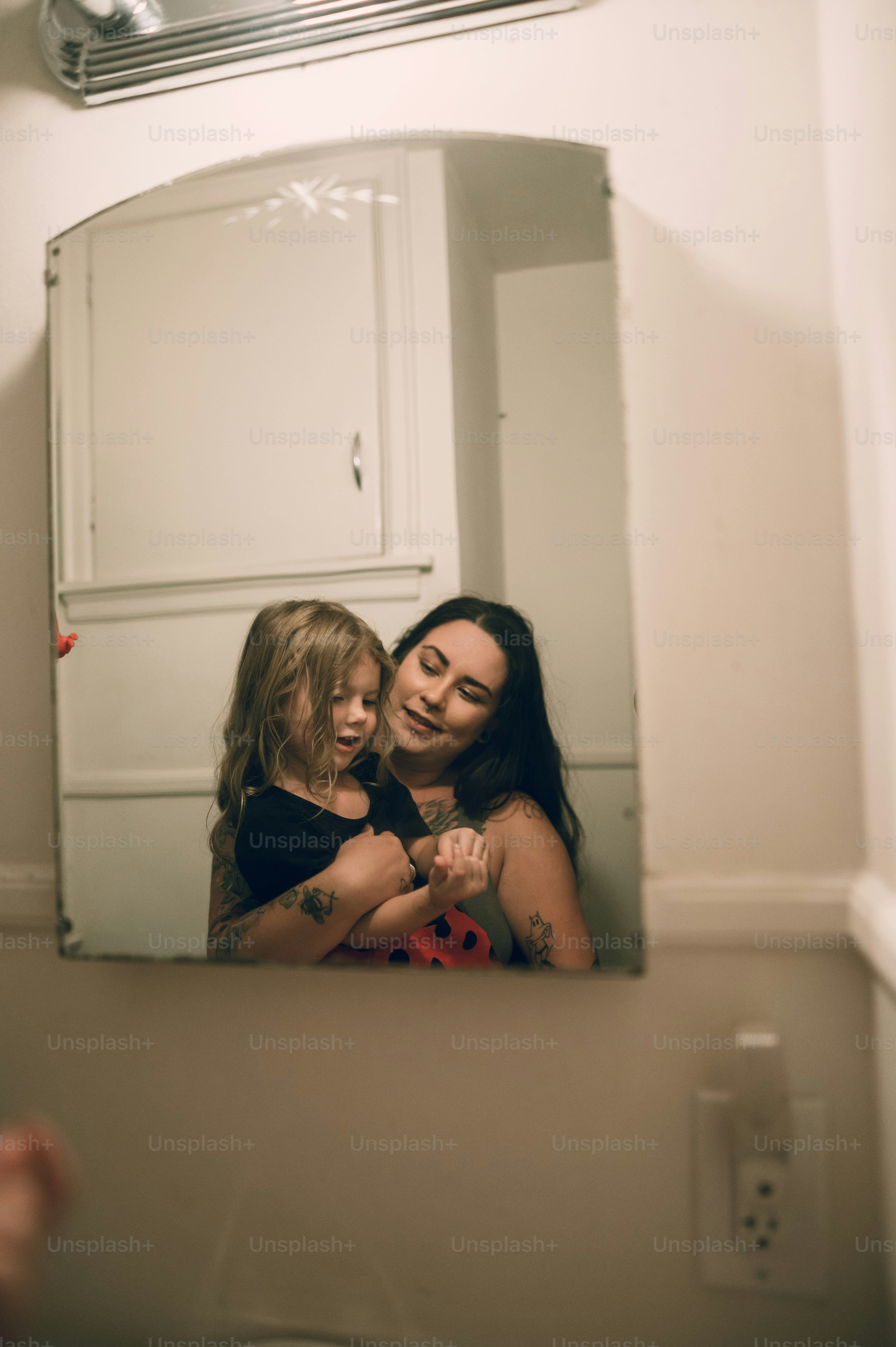 a woman and a little girl are looking in a mirror