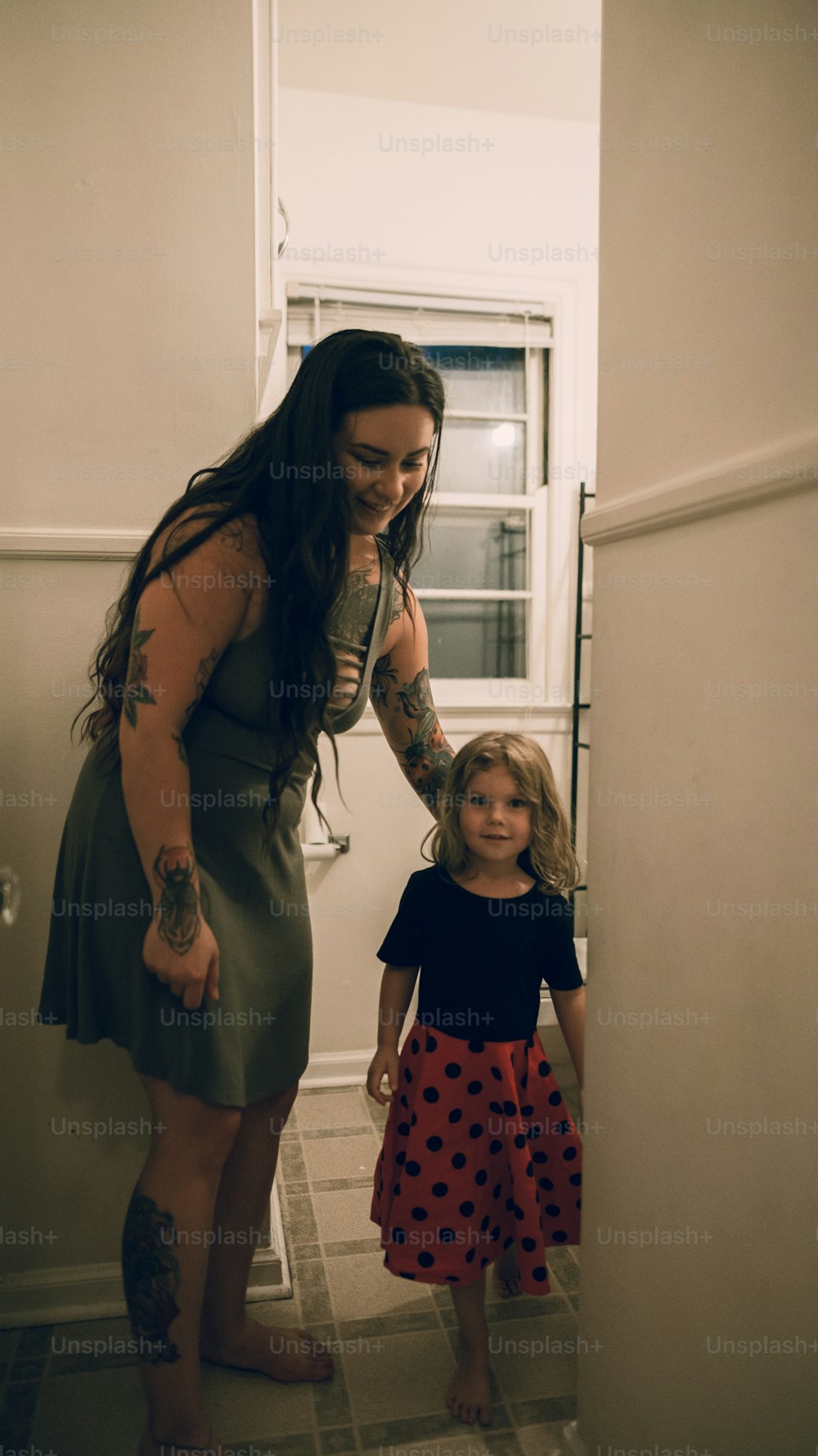 a woman standing next to a little girl