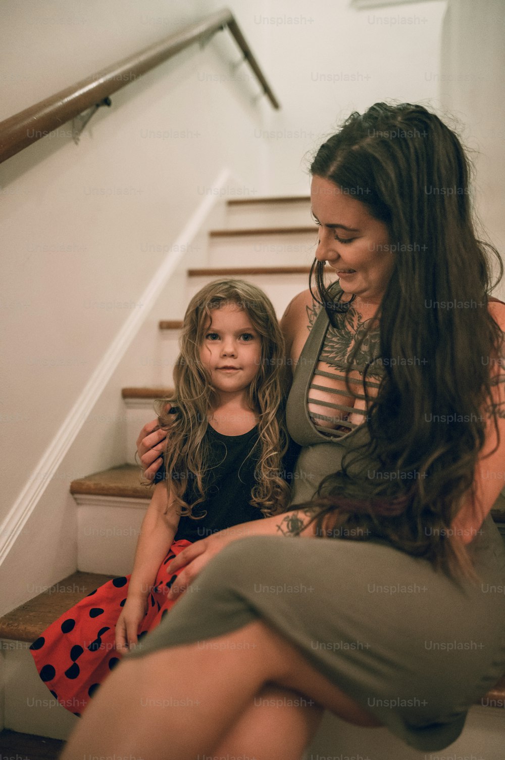 Une femme assise à côté d’une petite fille dans les escaliers