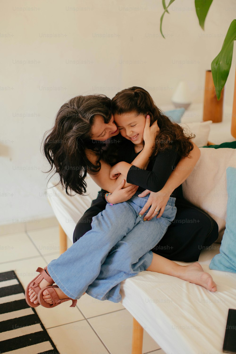 uma mãe e suas duas filhas abraçadas em um sofá