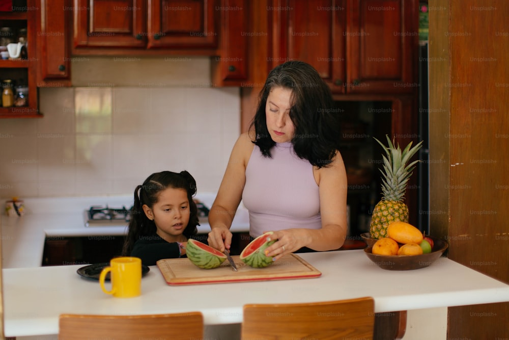 Eine Frau und ein kleines Mädchen schneiden eine Wassermelone