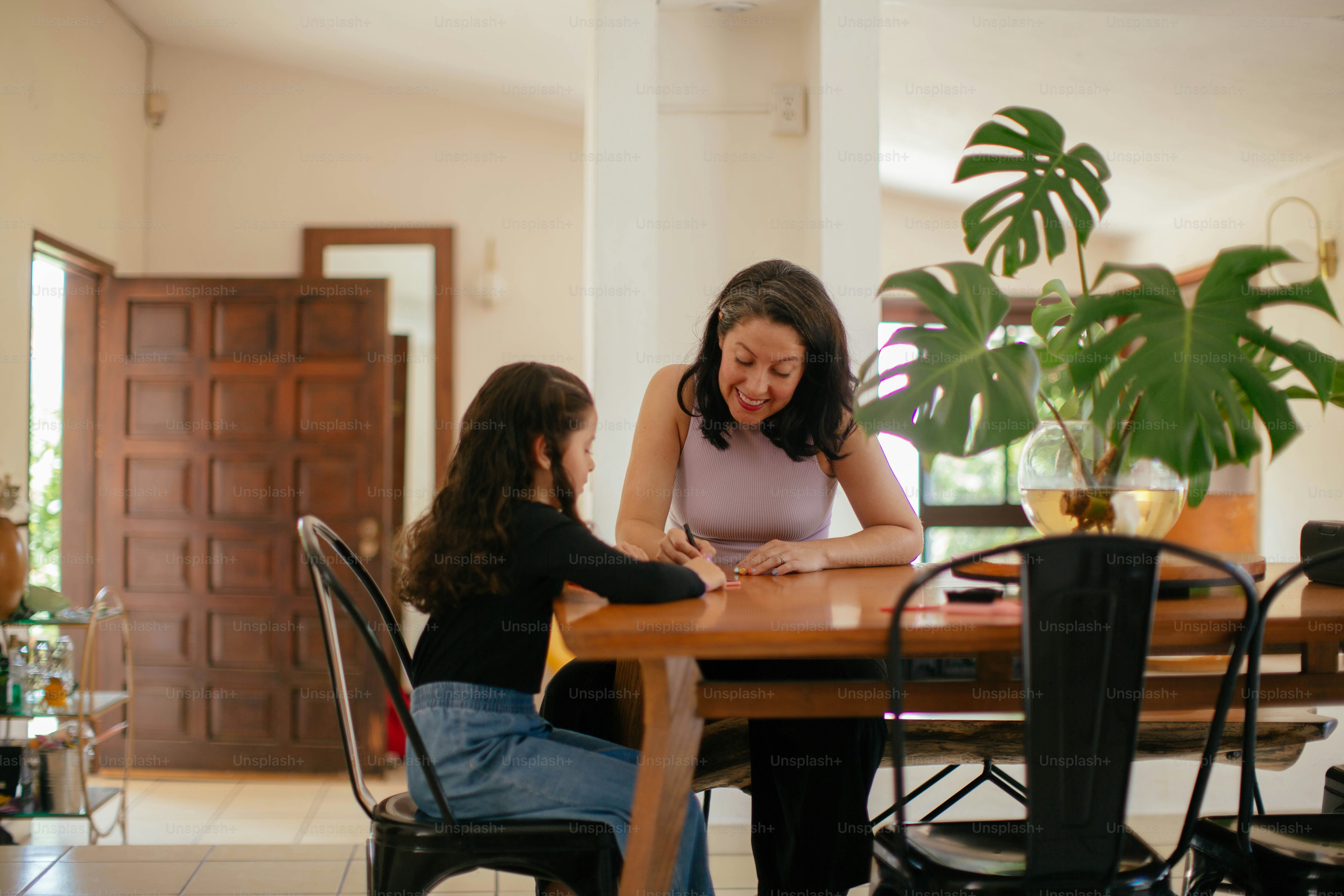 a woman sitting at a table with a little girl