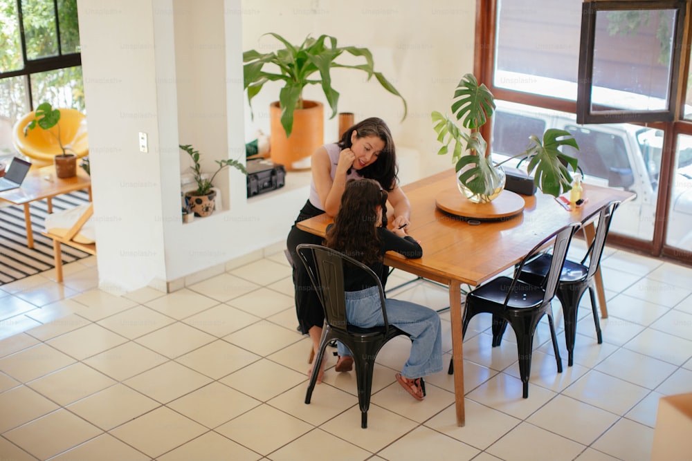 a couple of women sitting at a wooden table