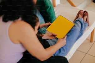 a woman sitting on a couch holding a yellow book