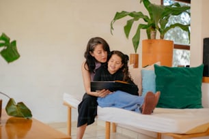 Deux filles assises sur un canapé regardant un livre