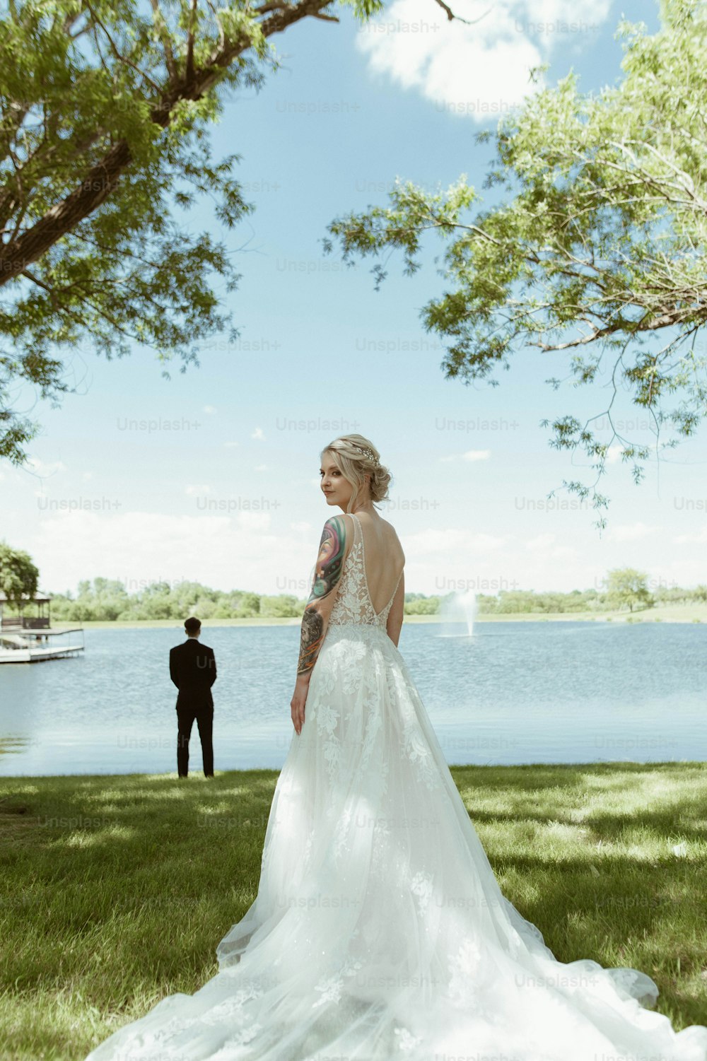 a woman in a wedding dress standing next to a lake