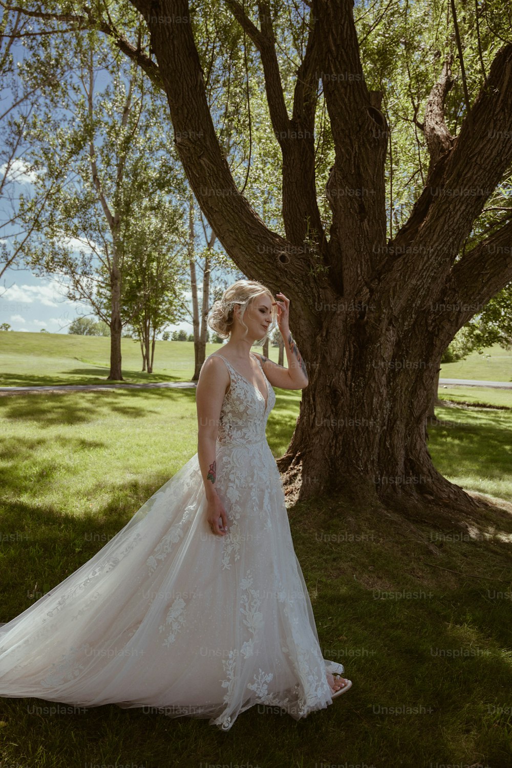 a woman in a wedding dress standing in front of a tree