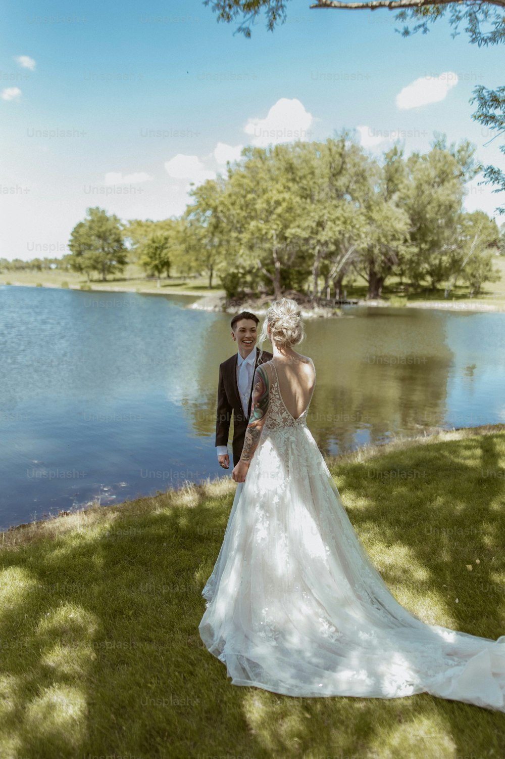 a bride and groom standing in front of a lake