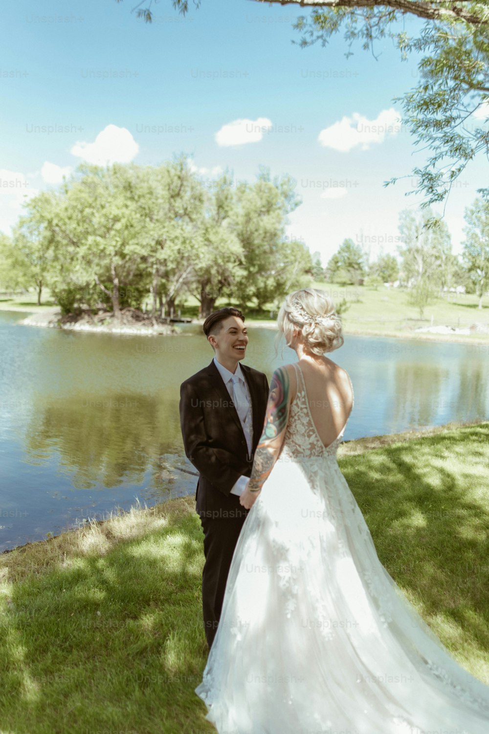 Una sposa e uno sposo in piedi vicino a un lago