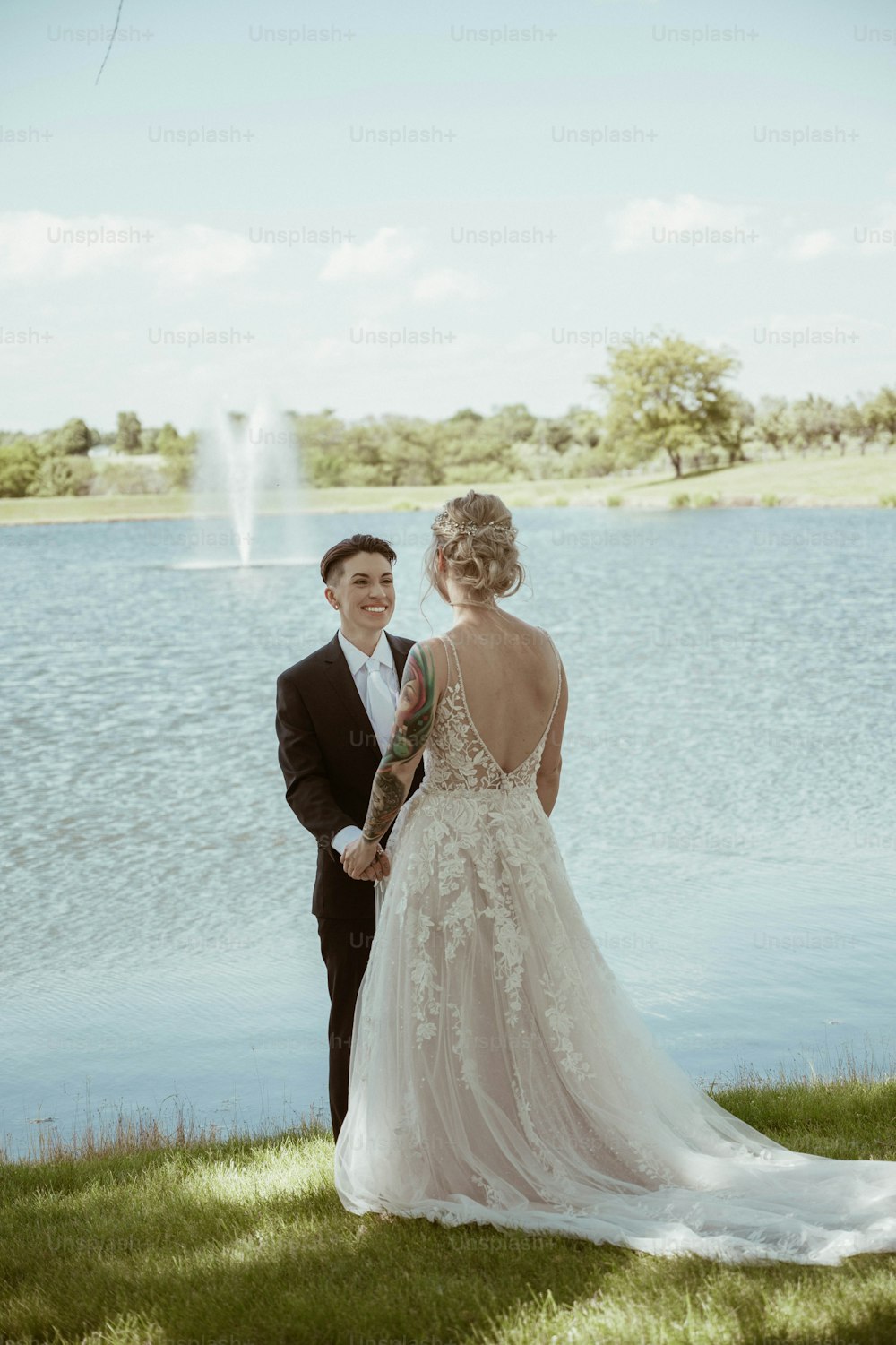 a bride and groom standing next to a lake