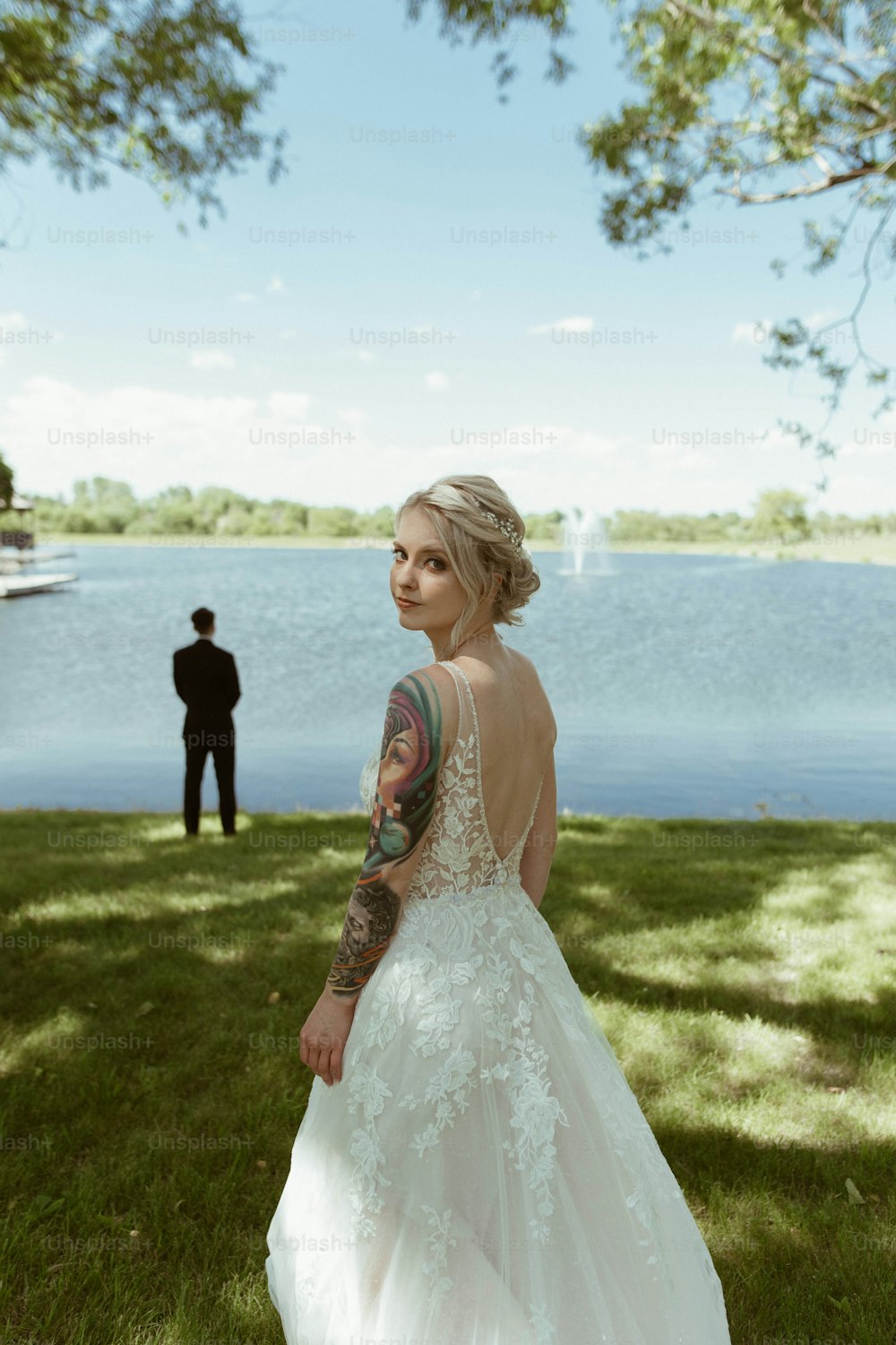 a woman in a wedding dress standing in front of a lake