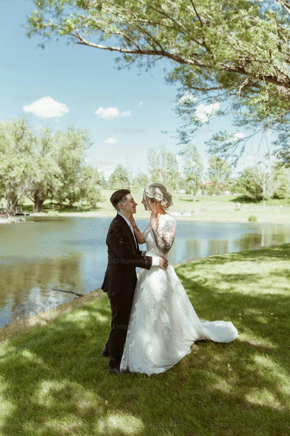 a bride and groom standing in front of a lake