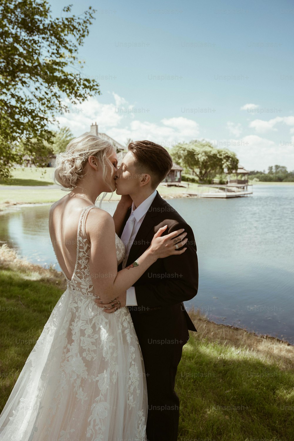Una novia y un novio besándose frente a un lago