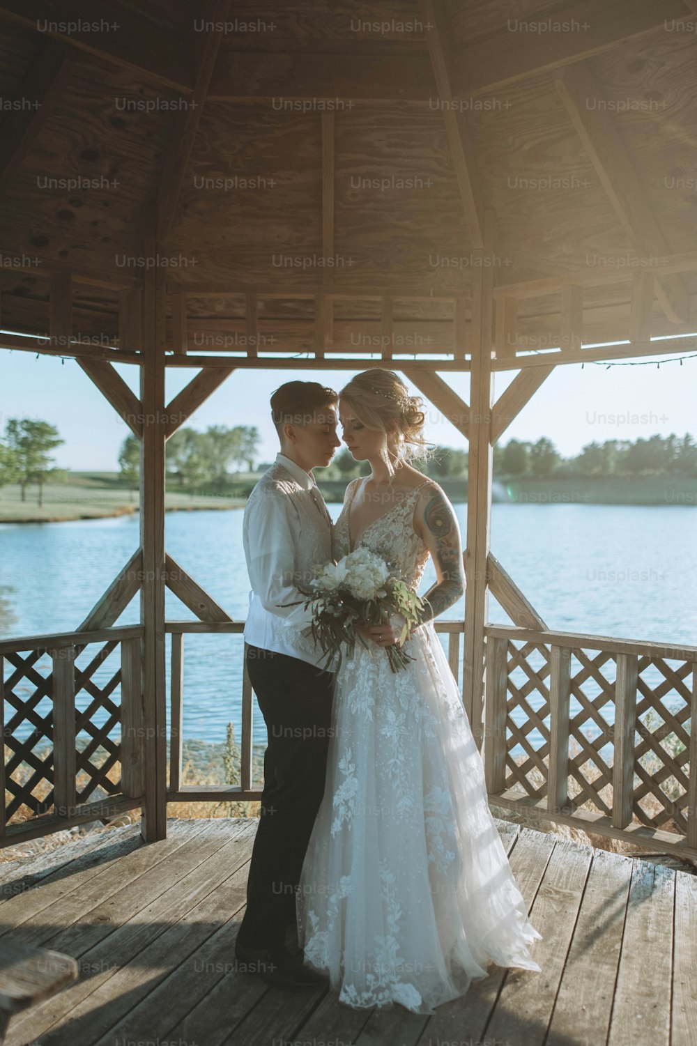 a bride and groom standing on a wooden deck next to a body of water