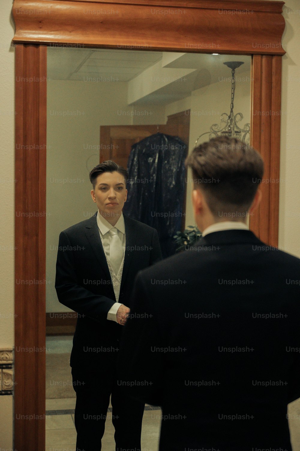 a man in a suit looking at himself in a mirror
