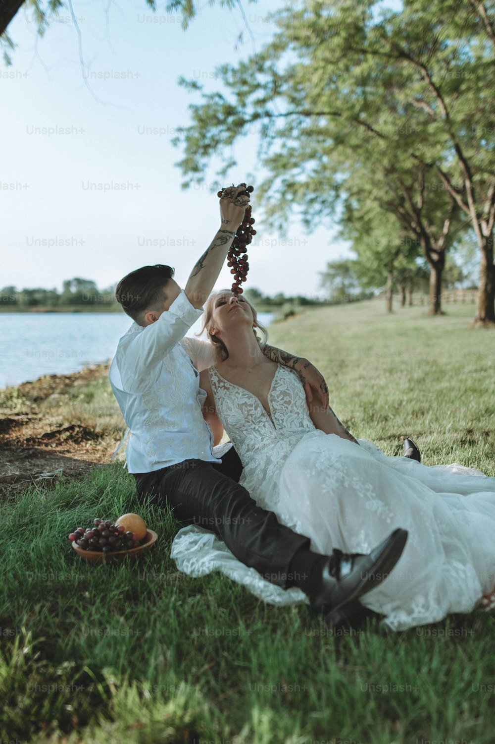 a bride and groom are sitting on the grass