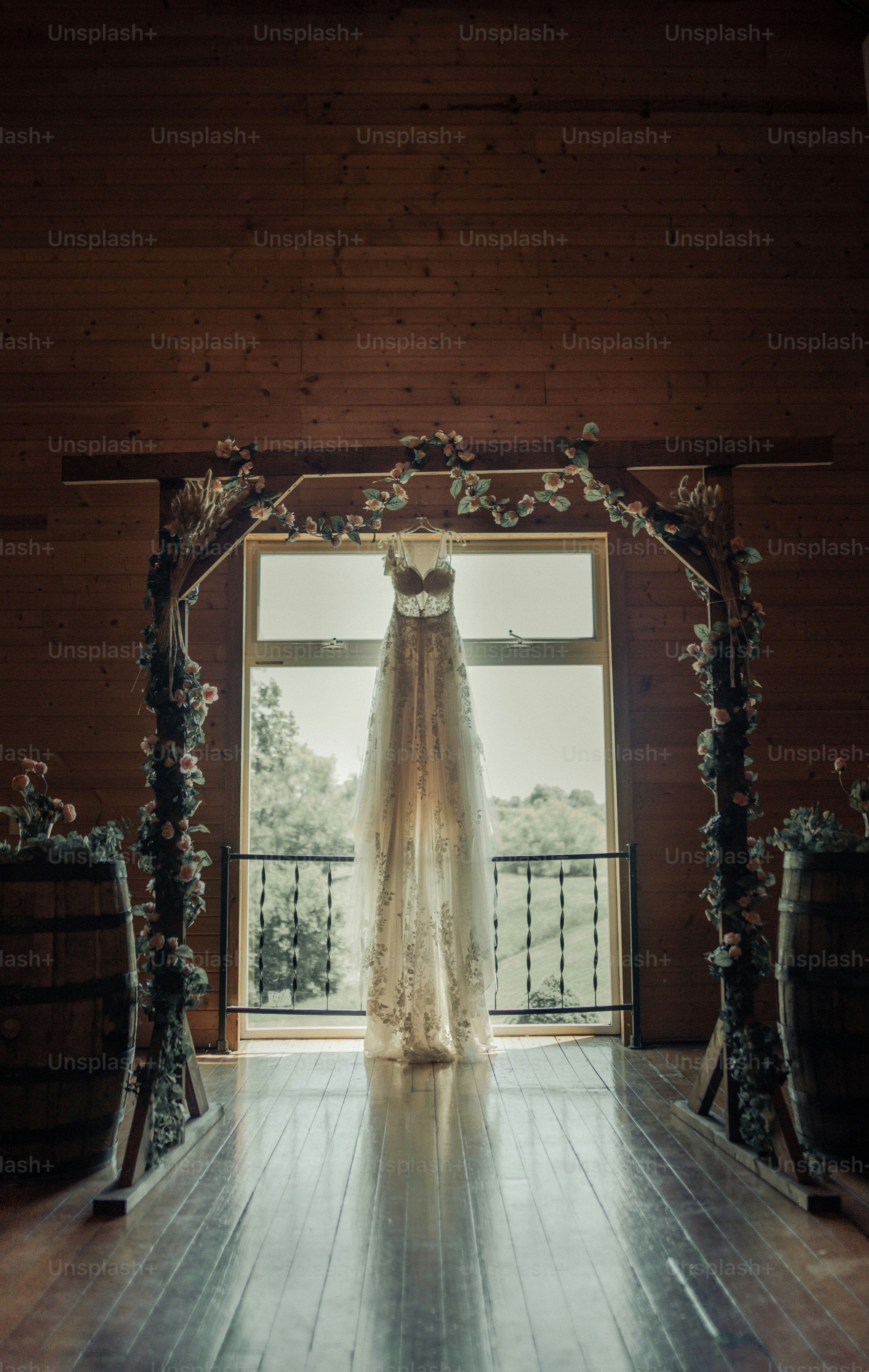 a wedding dress hanging in front of a window
