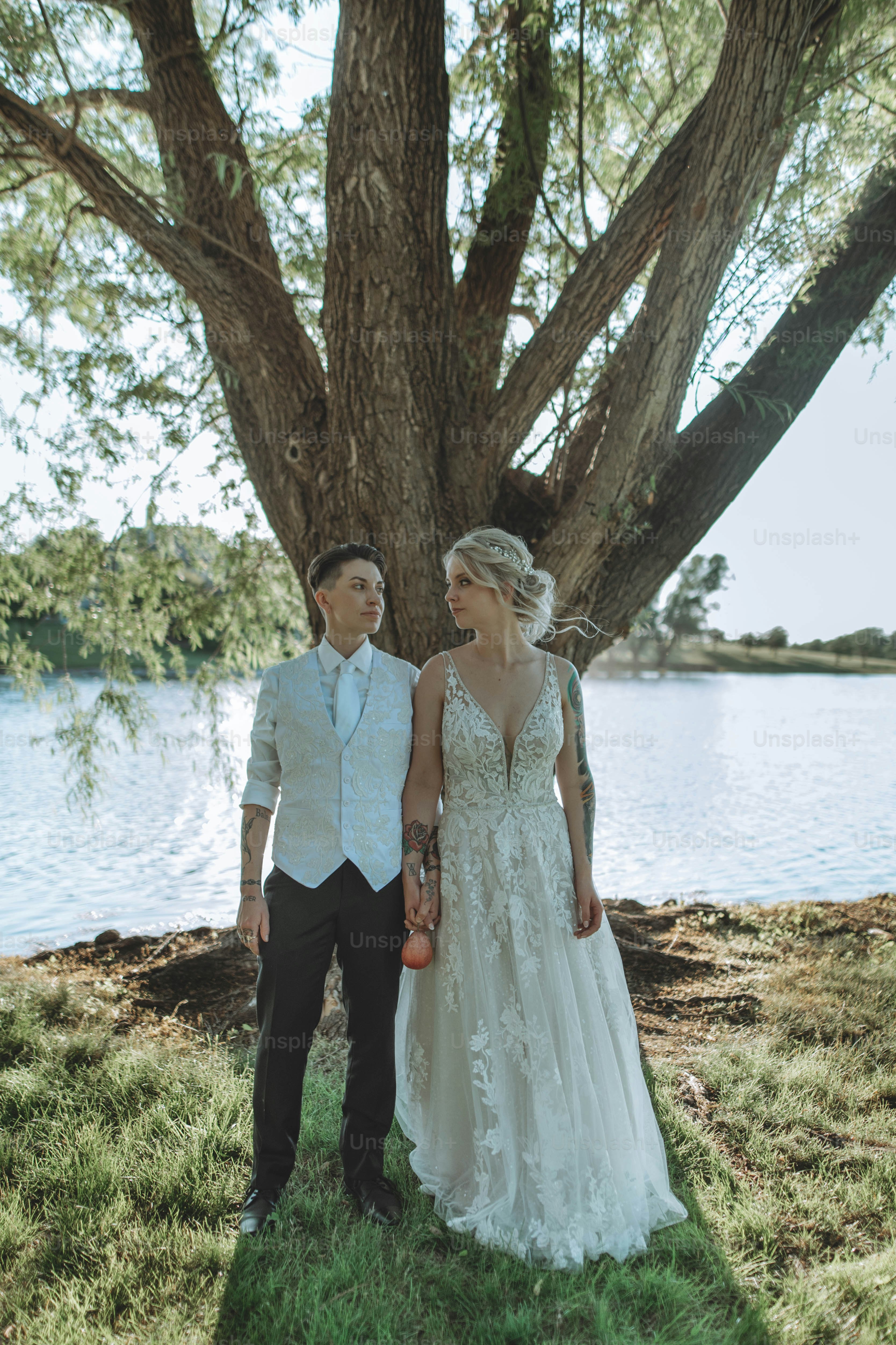 A bride and groom standing in front of a tree photo – Fashion Image on ...