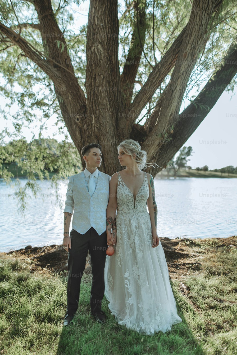 a bride and groom standing in front of a tree