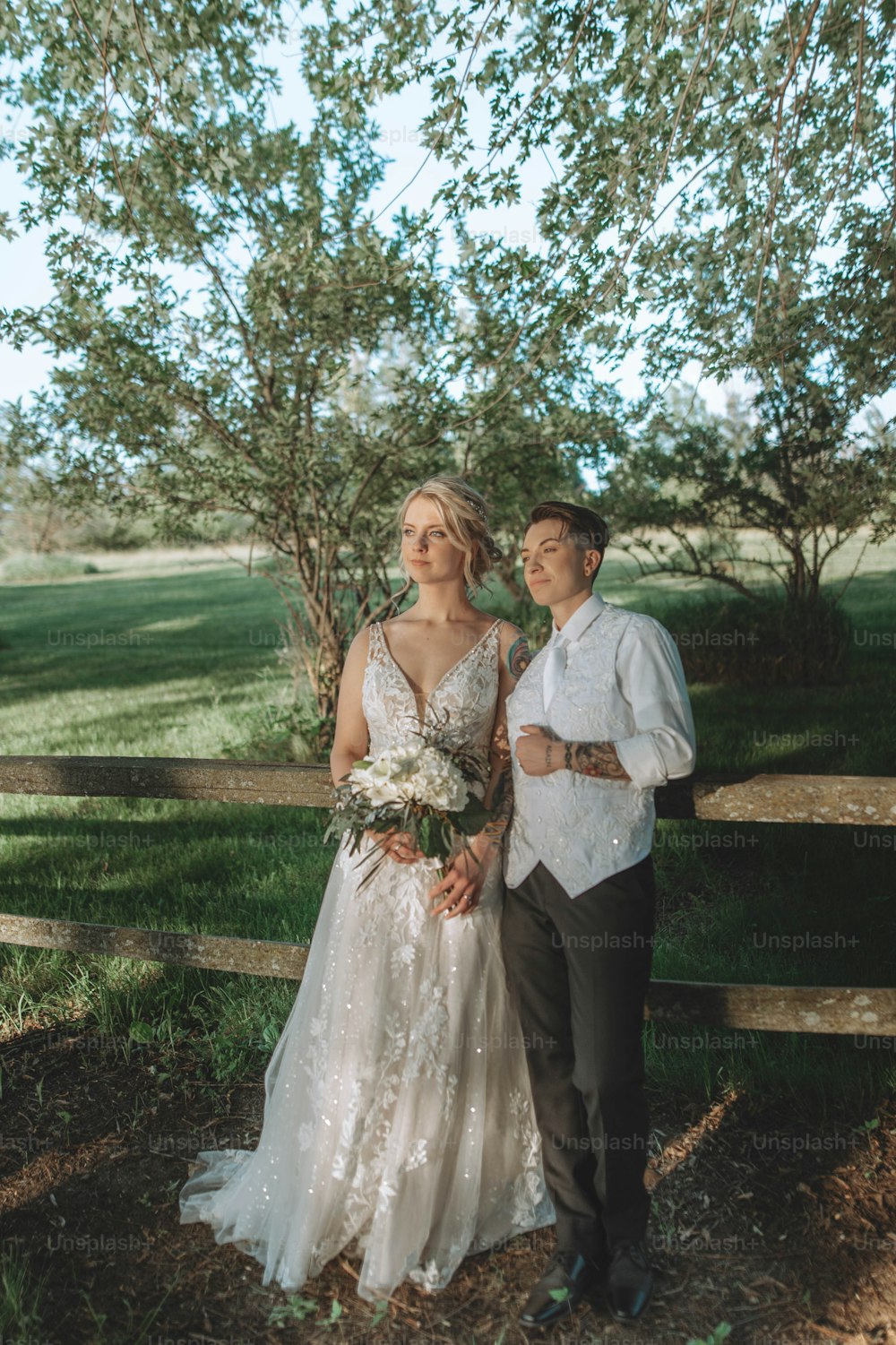 a bride and groom standing in front of a fence