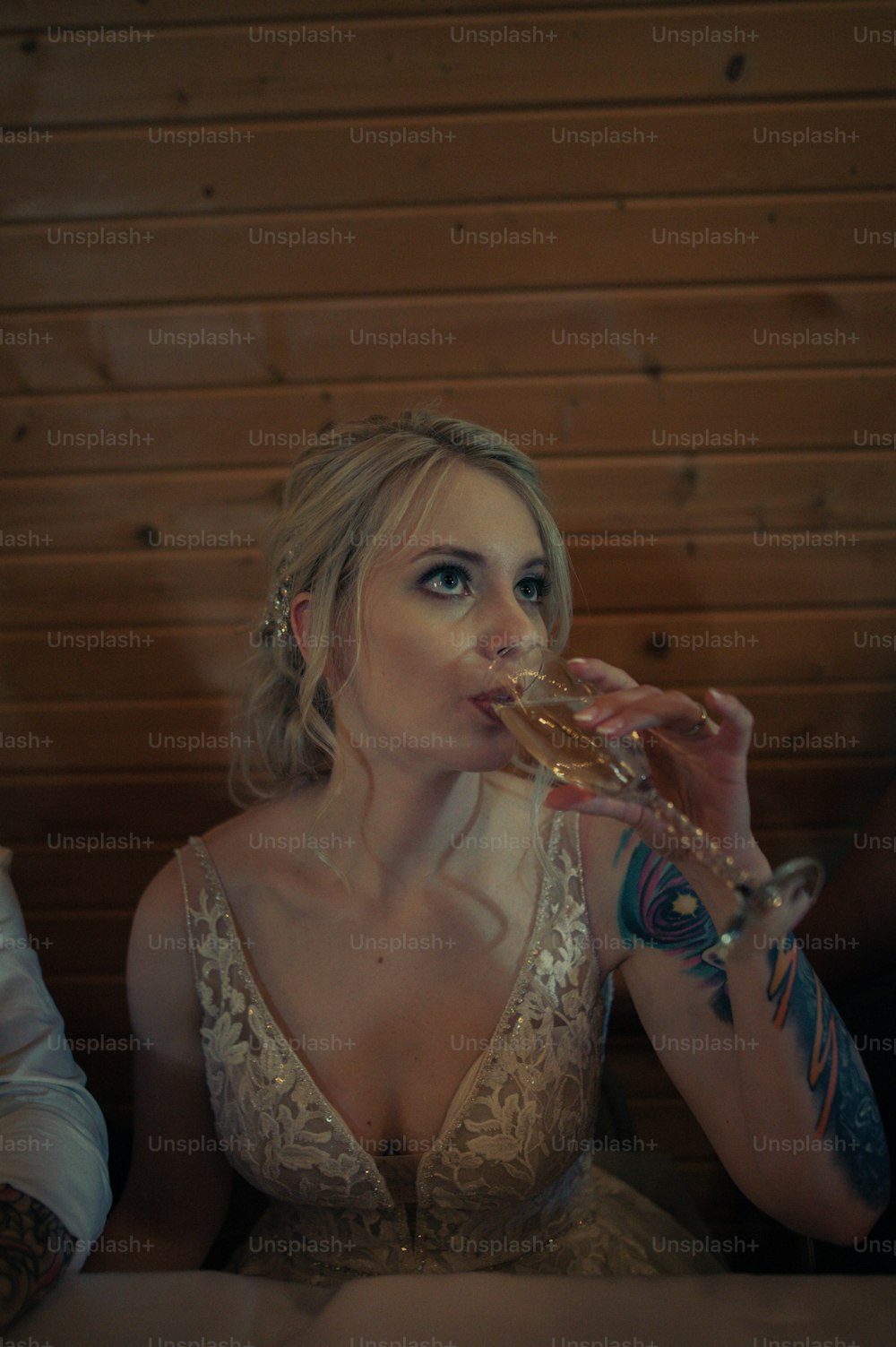 uma mulher em um vestido branco bebendo de uma taça de vinho