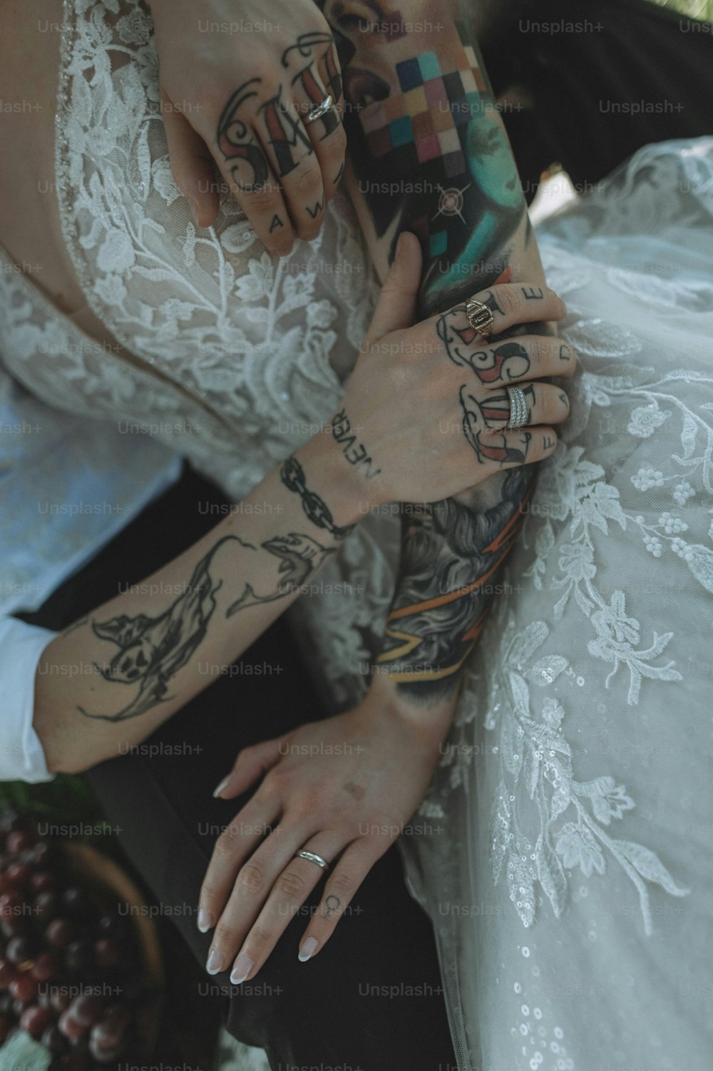 Eine Braut und ein Bräutigam, die Händchen halten, mit Tätowierungen auf den Armen