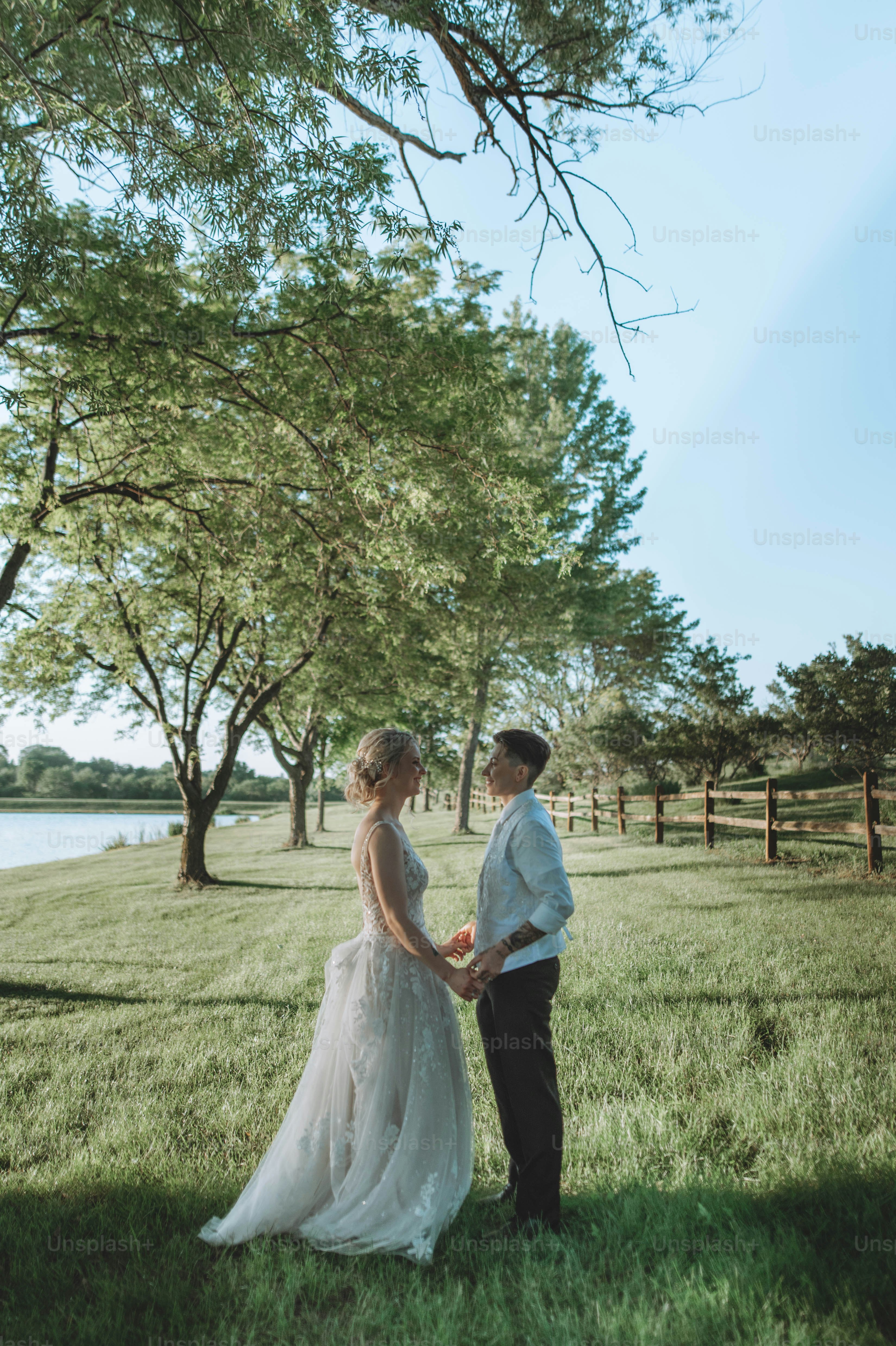 a bride and groom holding hands in a field